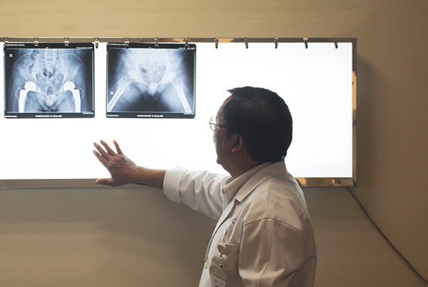 TS.BS Phạm Chí Lăng đang theo dõi phim chụp của một bệnh nhân đau khớp háng.