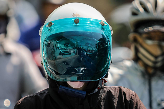 Cô gái mặc áo khoác, đội mũ bảo hiểm che kính kín mặt để chống nắng lúc giữa trưa trên đường ở TP HCM. Ảnh: Thành Nguyễn.